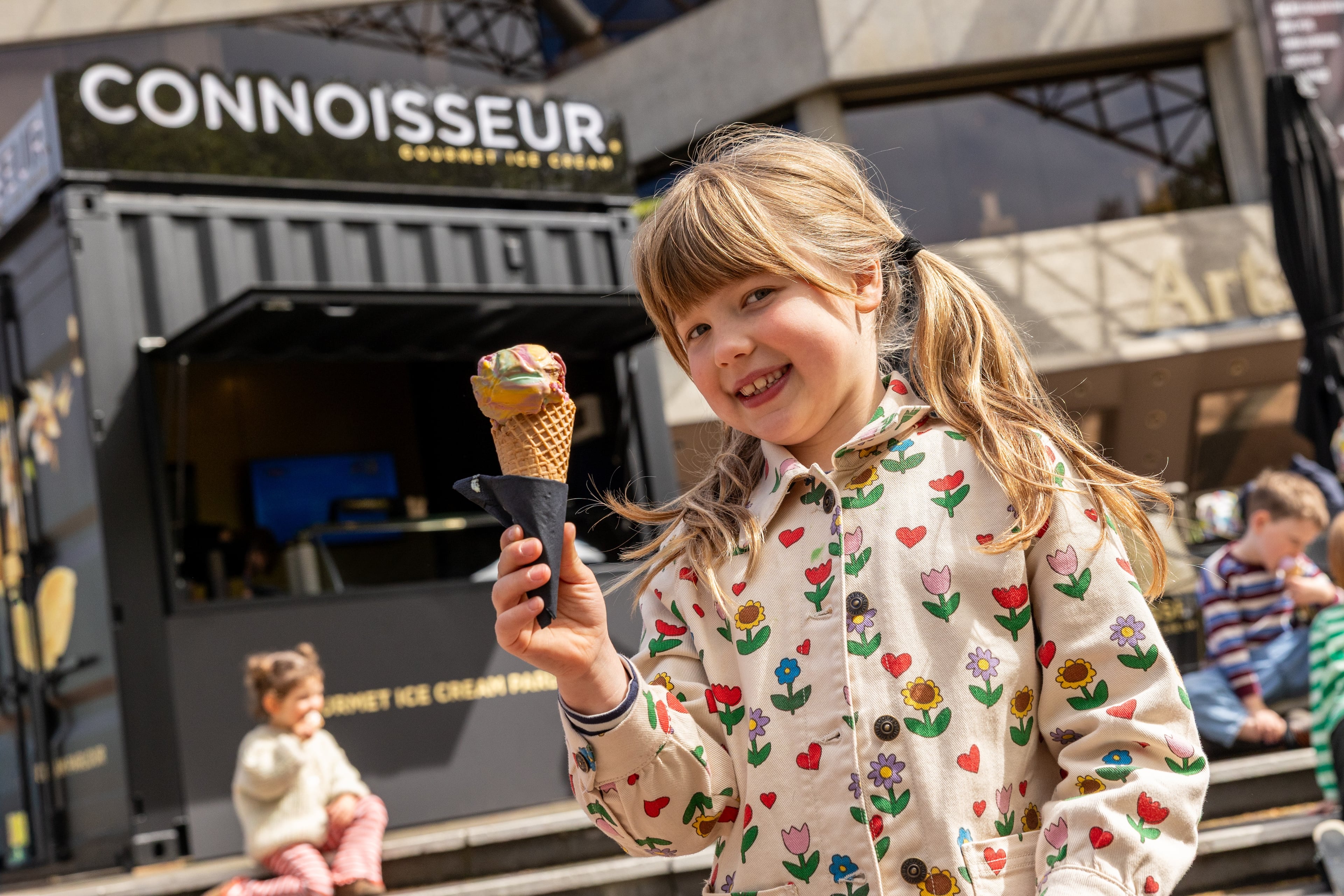 A child seated outside the Connoisseur ice cream stand at Arts Centre Melbourne.
