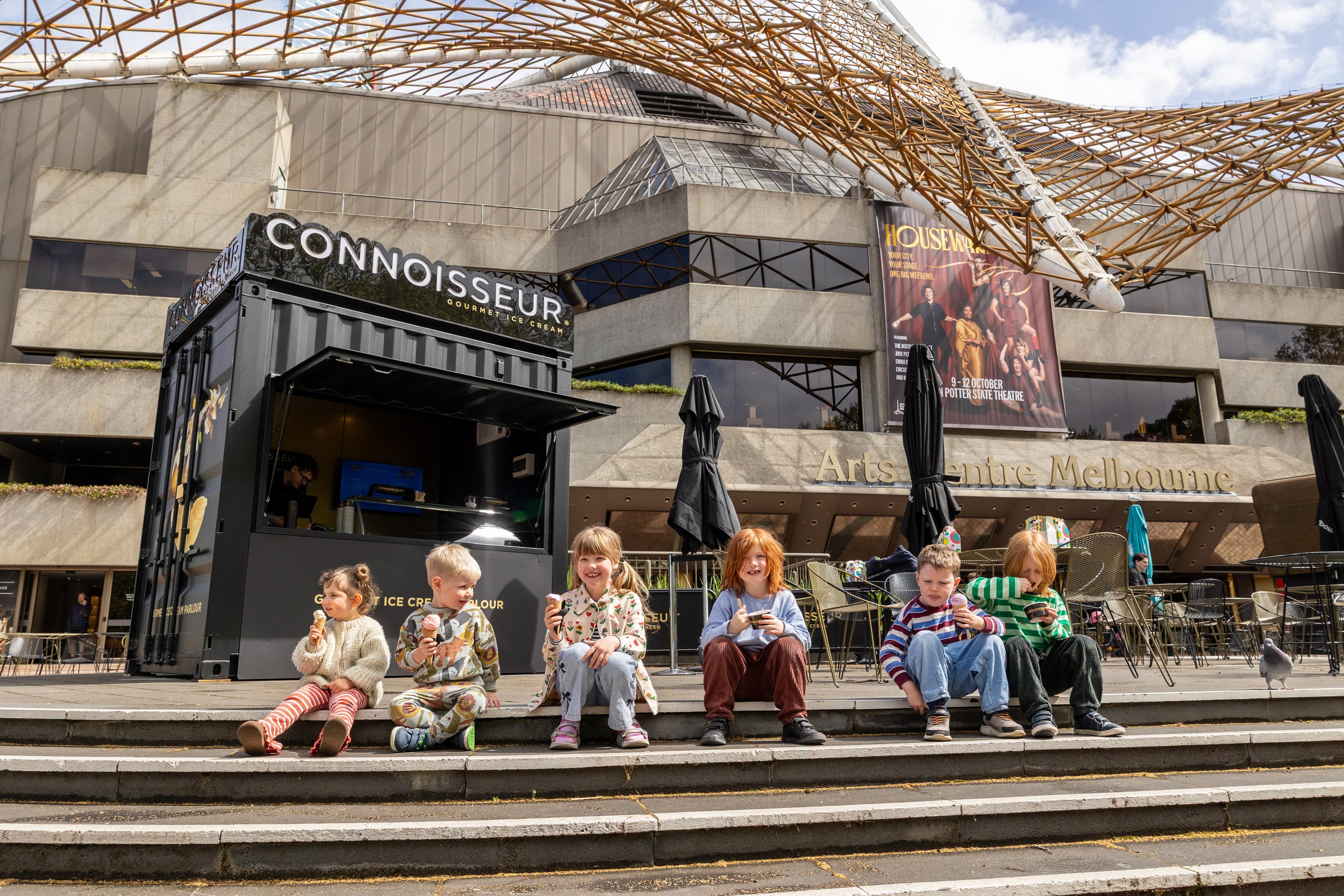 A child seated outside the Connoisseur ice cream stand at Arts Centre Melbourne.