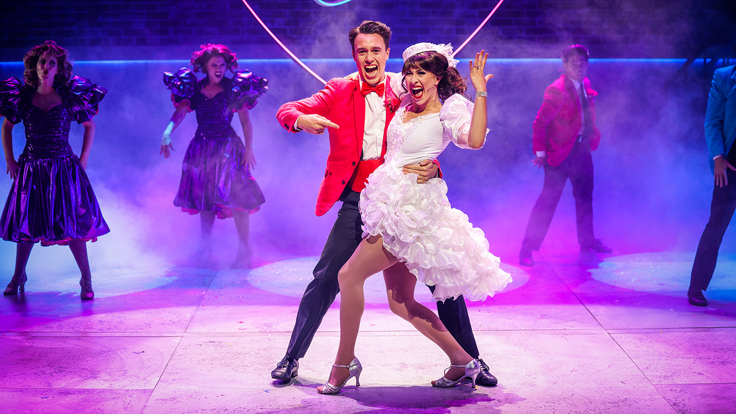 A production image from 'The Wedding Singer' depicting a just-married couple dancing together.