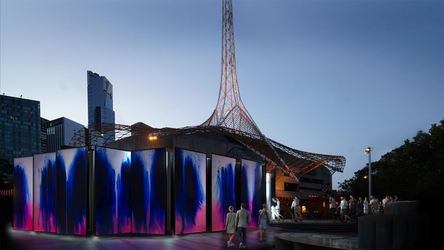 The Kaleidoscope exhibition sits on the Arts Centre Melbourne forcourt. The exterior is made of large panels, each with a dark blue inkblot on a white background that fades to pink. 