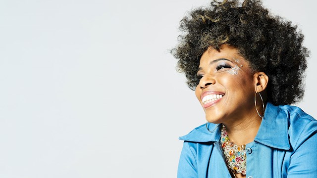 Macy Gray wearing a baby blue jacket, smiling.