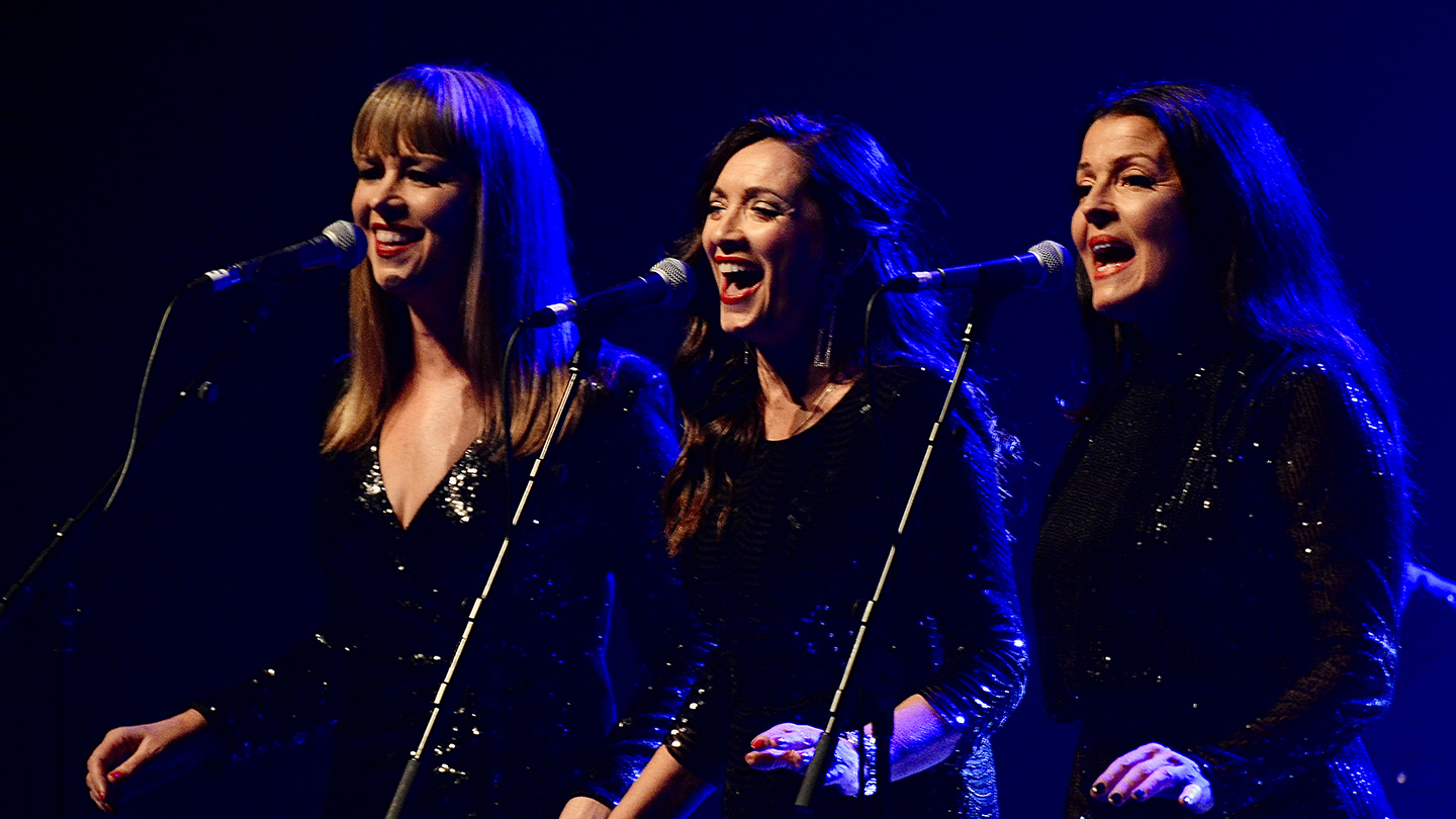 Three women singing on stage