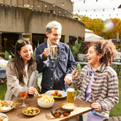Three young people eating and drinking in the courtyard of The Barre.