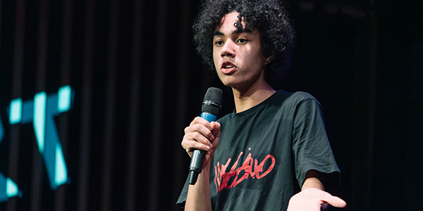 A young person on stage talking into a microphone.